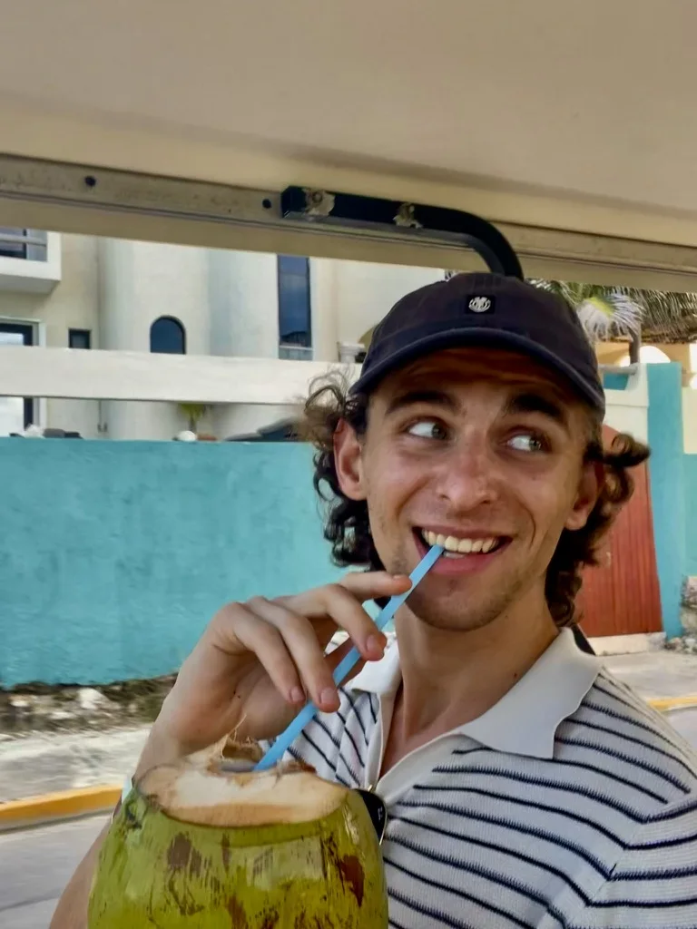 Tibo Vanleke smiling with a fresh coconut while travelling.